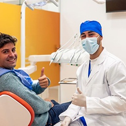 Happy dentist and patient making thumbs-up gesture