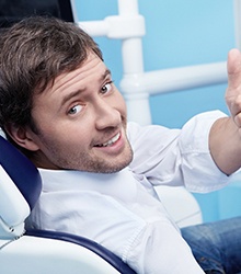 Dental patient looking over his shoulder while making thumbs-up gesture