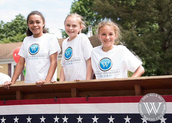 Three young dental patients smiling at community event