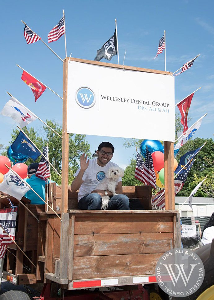 Smiling dental team member holding a dog on parade float