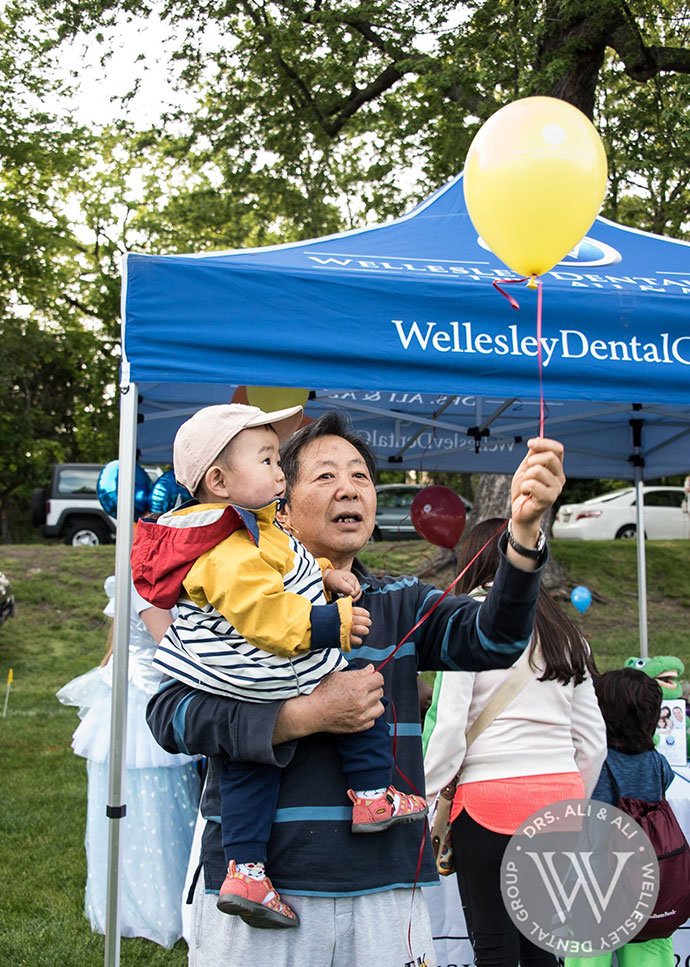 Caregiver and child holding a balloon at community event