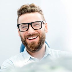 Man with glasses smiling after receiving cosmetic bonding  