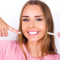 Woman with beautiful teeth holding Invisalign aligner