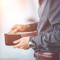 Man holding wallet, preparing to pay for dental treatment