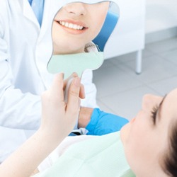 Dental patient using mirror to admire the results of cosmetic treatment