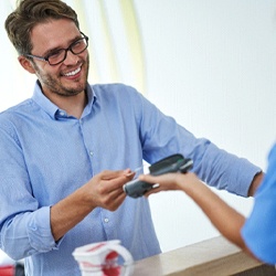 Patient handing over credit card to pay for veneers