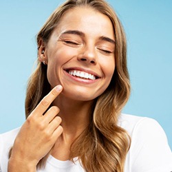 Happy young woman pointing at her beautiful white teeth