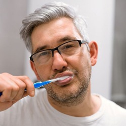 Middle-aged man brushing his teeth in bathroom