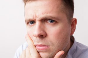 Frowning man, concerned about mouth sores with braces in Wellesley