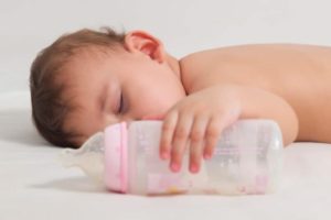 Sleeping infant holding a baby bottle