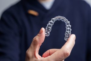 Close-up of man’s hand holding Invisalign aligner