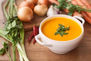 Bowl of creamy soup surrounded by vegetables