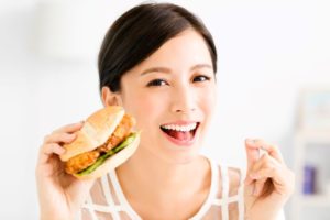 Woman with beautiful teeth, eating a burger