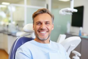 Happy male dental patient sitting upright in treatment chair