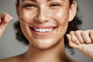 Smiling woman flossing her teeth