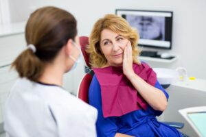 Middle-aged woman talking with dental team member 