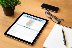 Dental insurance form on tablet next to notebook 