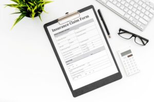 Insurance claim form next to glasses and calculator 